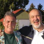 Two men standing next to each other in front of a building.