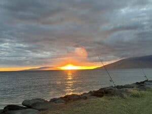 A fishing rod is on the shore of a lake.