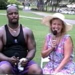 A man and woman sitting on the grass with microphones.