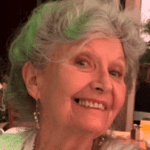 A woman with grey hair smiling at the camera.