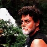 A man with a beard and mustache wearing black shirt.